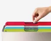 A hand is shown selecting one of several colored cutting boards from a holder. Podgląd zdjęcia produktu