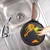 A hand is cleaning a dirty frying pan in a kitchen sink. Náhľad obrázku produktu
