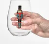A hand holding a clear glass with a nutcracker decoration. Produktbild-Vorschau