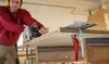 A person is using a circular saw to cut a piece of particle board on a workbench. Podgląd zdjęcia produktu