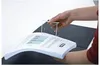 A hand holding a document binder clip over an open binder. Voir les images du produit