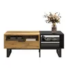 A modern coffee table with a wood and black color block design, featuring shelves and a drawer, set against a white background. Produktbild-Vorschau