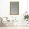 A mirror is displayed on a white wall above a small side table with decorative items, next to an armchair and a potted plant. Produktbild-Vorschau
