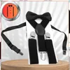 A black bow tie and suspender set is displayed on a white background, with a wooden surface at the bottom. Produktbild-Vorschau