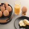 A breakfast scene with a multi-egg cooker, a glass of orange juice, and toast on a plate. Produktbild-Vorschau