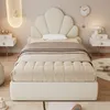 A bedroom scene featuring a beige upholstered bed with a shell-shaped headboard. Voir les images du produit