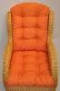 A close-up view of a wicker chair with an orange cushion. Produktbild-Vorschau