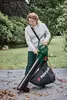 A woman is using a leaf blower/vacuum in a garden setting. Produktbild-Vorschau