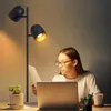 A young woman is working at a desk with a laptop, illuminated by a floor lamp. Produktbild-Vorschau