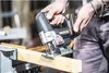 A person is using a jigsaw to cut a piece of wood. Podgląd zdjęcia produktu