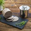 A loaf of meat and slices of meat are presented on a dark slate board, with a stainless steel container and herbs in the background, set against a wooden surface. Podgląd zdjęcia produktu