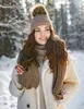 A young woman wearing a winter hat and scarf in a snowy forest. Voir les images du produit