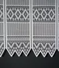 A close-up view of a white lace curtain with a geometric pattern. Produktbild-Vorschau