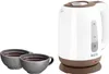 A white and brown electric kettle with a water level indicator sits next to two cups of dark liquid. Náhľad obrázku produktu