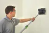 A man is using a wallpaper perforator tool on a textured wall. Podgląd zdjęcia produktu