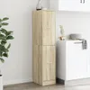 A tall, narrow cabinet with two doors, made of wood-look material, stands in a room with a plant and kitchen counter in the background. Anteprima dell’immagine prodotto