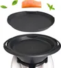 A piece of salmon and basil leaves are shown above a black silicone steaming insert and a black silicone baking dish, which are placed on top of a white appliance. Produktbild-Vorschau