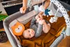 A baby lying in a crib with toys hanging above. Produktbild-Vorschau