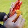 A person's hands holding an orange and brown toy blaster outdoors. Podgląd zdjęcia produktu