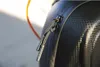 Close-up of a black zipper with two pull tabs on a textured black surface, with a blurred orange object in the background. Produktbild-Vorschau