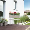 A planter stand with flowers on a wooden deck next to a white house. Voir les images du produit