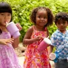 Three young children are outdoors, each holding a sippy cup. Produktbild-Vorschau