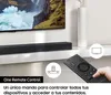A hand holding a remote control in front of a TV and soundbar setup. Voir les images du produit