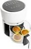 A white air fryer with a glass bowl, containing four muffins, is shown against a white background. The top of the air fryer has a black control panel with touch buttons and icons. Produktbild-Vorschau