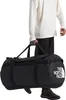 A person is carrying a large black duffel bag. Produktbild-Vorschau