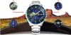 A watch is displayed in the center with four close-up views of its features around it, set against a backdrop of a desert landscape with rock formations and a road. Produktbild-Vorschau