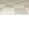 A close-up, angled view of a checkered rug with cream and beige squares. Anteprima dell’immagine prodotto