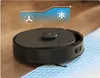 A black robot vacuum cleaner is shown on a wooden floor transitioning to a tiled floor with a blue grid pattern. An overlay graphic indicates increasing fan speed. Produktbild-Vorschau
