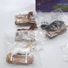 Several toy horses are individually packaged in clear plastic bags, some with cardboard inserts, arranged on a white surface. A portion of a purple box with product images is visible in the upper right corner. Náhľad obrázku produktu