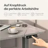 A desk with a laptop, coffee cup, and charging devices, with a hand pressing buttons on the desk control panel. Produktbild-Vorschau