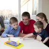 A family is gathered around a table playing a finger basketball game. Produktbild-Vorschau