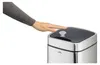 A hand is shown hovering over the lid of a silver sensor trash can, activating its motion sensor. Podgląd zdjęcia produktu