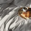 A breakfast tray with a croissant and coffee on a bed. Produktbild-Vorschau