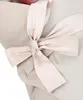 A close-up of a beige baby swaddle blanket tied with a light pink bow. Produktbild-Vorschau
