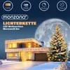 A house decorated with Christmas lights at night, with a large moon in the background. Produktbild-Vorschau