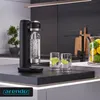 A modern kitchen counter with a black soda maker, two glasses with lime slices, and a jar of lemons and limes. Produktbild-Vorschau
