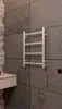 A bathroom towel warmer mounted on a tiled wall. Produktbild-Vorschau