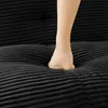 A person's foot pressing into a black, textured sofa cushion. Produktbild-Vorschau