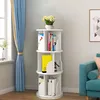A white rotating bookshelf filled with books and a vase of flowers on top, placed in a room with blue curtains and a sofa. Produktbild-Vorschau
