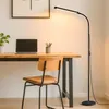 A floor lamp illuminates a desk with a laptop and a chair. Produktbild-Vorschau