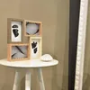 A collage of four picture frames is displayed on a white table, with a seashell placed next to them. A tall, ornate white mirror frame is visible on the right side of the image. Náhled obrázku produktu