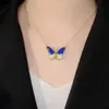 Goldener Schmetterlingsanhänger-Halskette mit blauem Emaille und klaren Strasssteinen, am Hals einer Person getragen Náhľad obrázku produktu