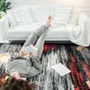 A person is lying on a rug in front of a white sofa, reading a book. Anteprima dell’immagine prodotto