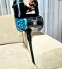 A hand is holding a black and blue vacuum cleaner and is using it on a beige sofa. Podgląd zdjęcia produktu