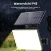 A solar-powered floodlight with a separate solar panel, shown in a rainy outdoor setting. Produktbild-Vorschau