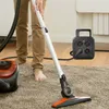 A person is vacuuming a carpet with a vacuum cleaner, and a power strip with multiple outlets and USB ports is visible in the background. Podgląd zdjęcia produktu